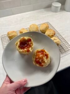 Classic British scone split and served with strawberry jam on a plate