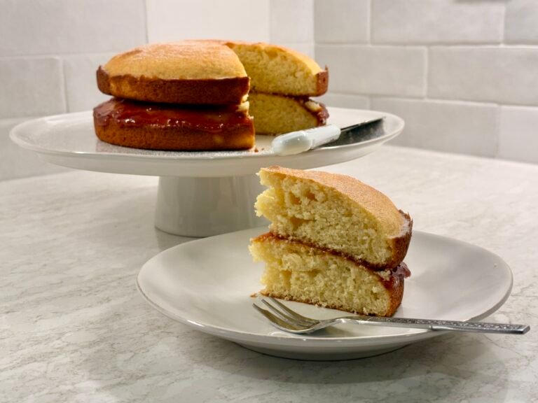 Slice of Victoria sponge cake with jam on a plate