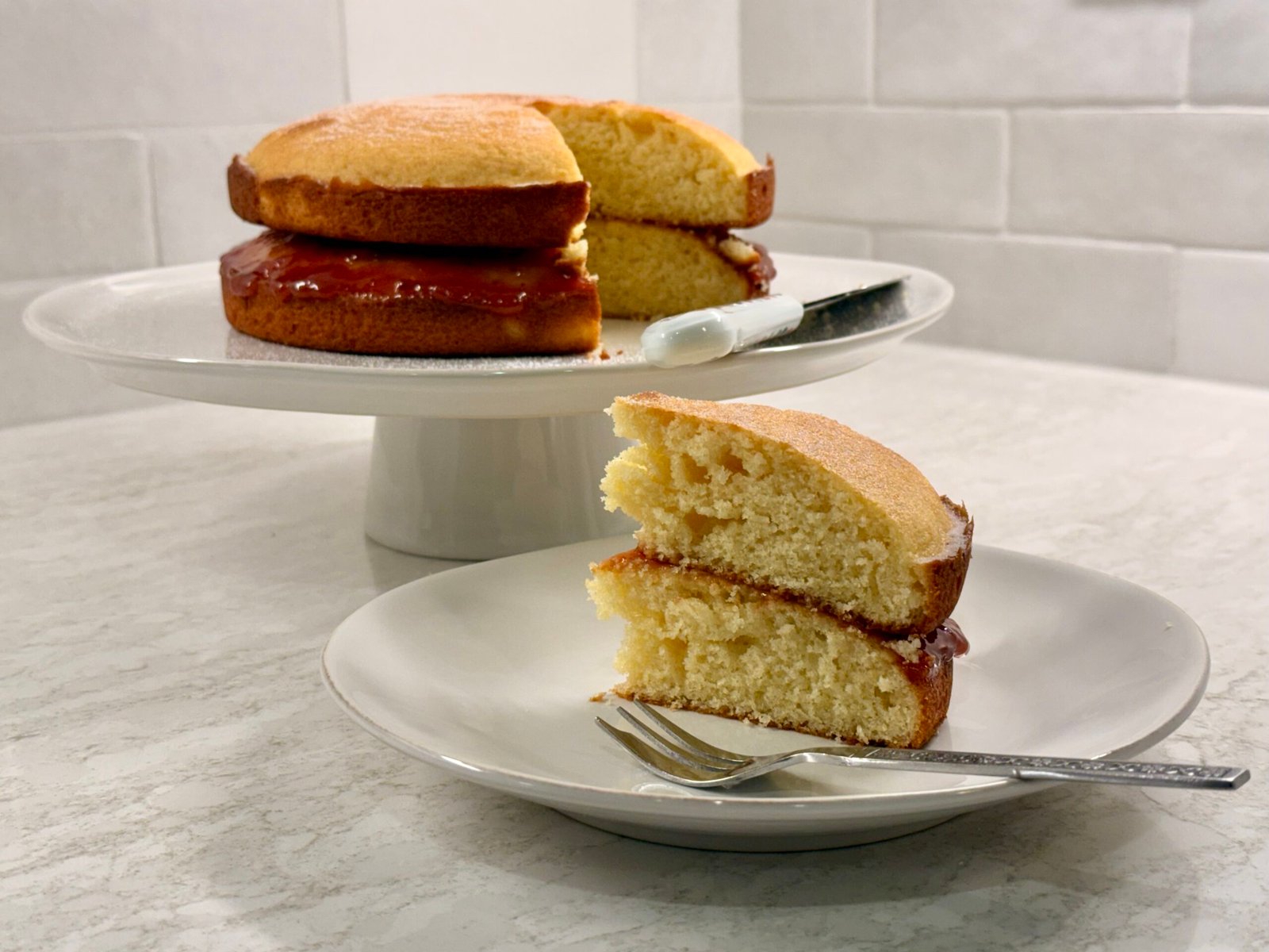 Slice of Victoria sponge cake with jam on a plate