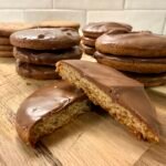Homemade British digestive biscuits with milk chocolate coating, stacked on a wooden board