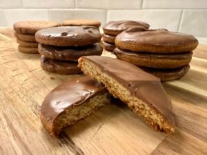 Homemade British digestive biscuits with milk chocolate coating, stacked on a wooden board