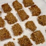 Classic British flapjacks made with rolled oats and golden syrup, cut into squares on parchment paper