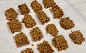 Classic British flapjacks made with rolled oats and golden syrup, cut into squares on parchment paper