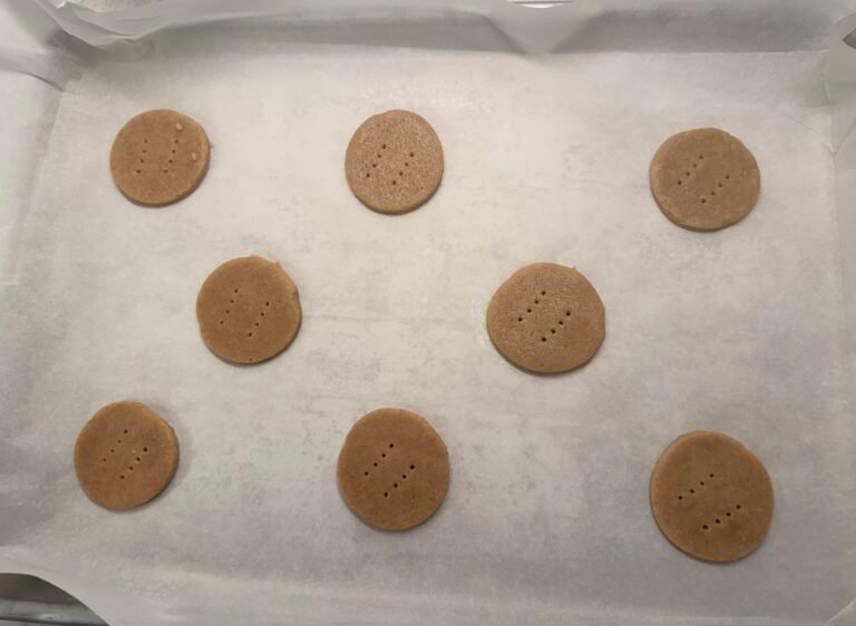 Uncooked British digestive biscuits on a baking tray with parchment paper