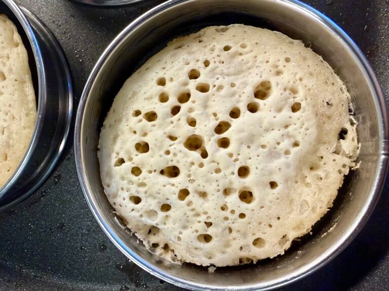 British crumpet baking in a crumpet ring in a skillet.