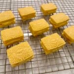 Golden custard cream biscuits on a wire cooling rack.