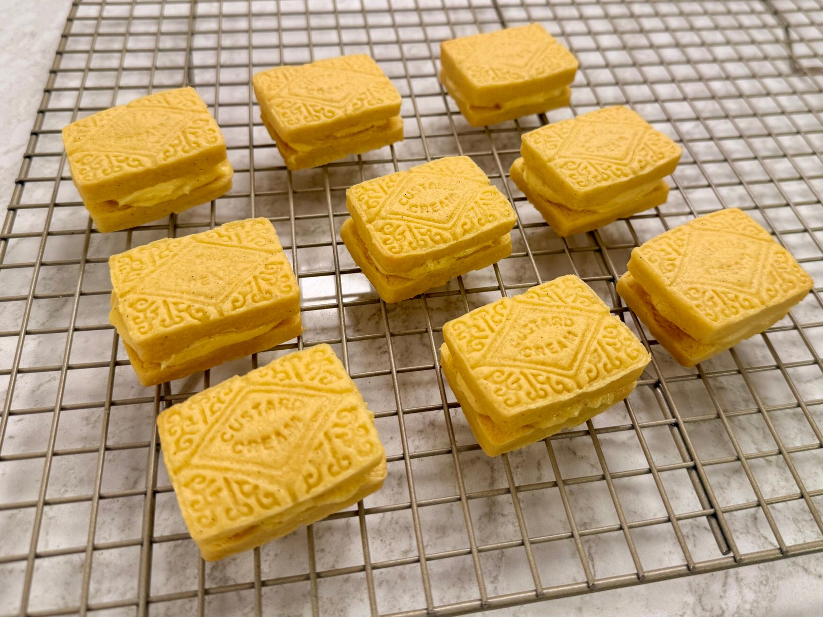 Golden custard cream biscuits on a wire cooling rack.