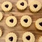 Homemade British Jammy Dodgers with fluted edges, heart-shaped centers, and raspberry jam filling.